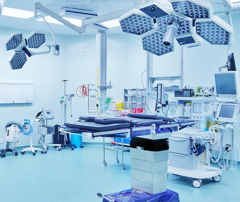 Surgical - Modern operating room equipped with surgical lights, an operating table, monitors, and various medical equipment; the room is clean and brightly lit.